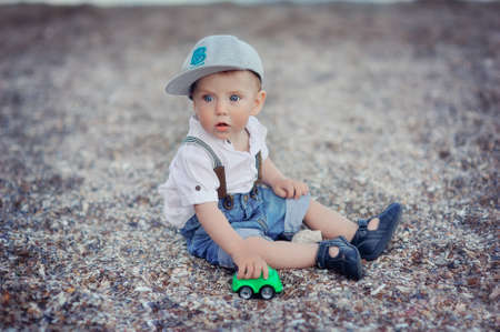 by the sea on the pebbles sitting cute kid in jeansの写真素材