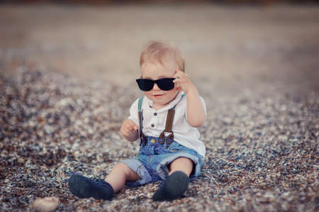 by the sea on the pebbles sitting cute kid in jeansの写真素材