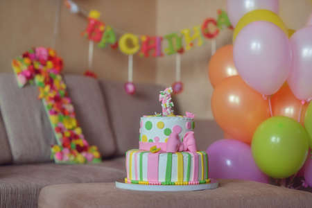 against the background of festive decorations from balloons colored cake with candlesの写真素材