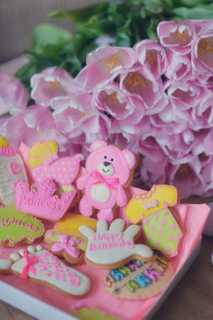 on the table colored different figures of biscuits and a bouquet of tulipsの写真素材