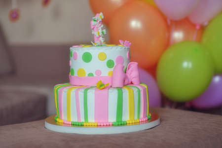 against the background of festive decorations from balloons colored cake with candlesの写真素材