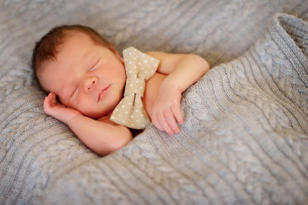 on a bed in a knitted blanket sleeping babyの写真素材