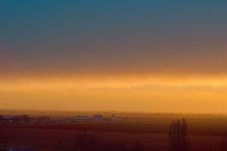 beautiful bright sunset on the horizon over the houses and fieldsの写真素材