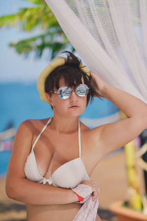 under a canopy near the sea woman in swimsuit and sunglassesの写真素材
