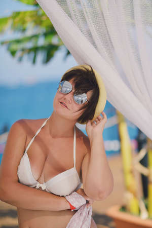under a canopy near the sea woman in swimsuit and sunglassesの写真素材