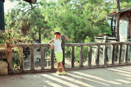 against the backdrop of pines boy in hat standing near an old wooden fenceの写真素材