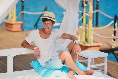 against the sea under a white canopy resting man in a straw hatの写真素材
