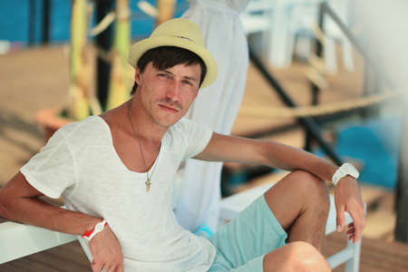against the sea under a white canopy resting man in a straw hatの写真素材