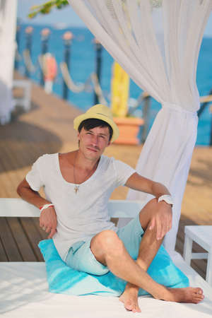 against the sea under a white canopy resting man in a straw hatの写真素材