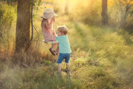 in the forest in sunny sunshine swing ride boy with girlの写真素材
