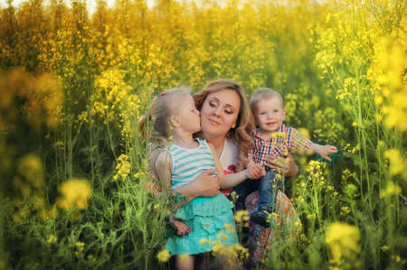 in the blossoming field and sun mother with a young daughter and sonの写真素材