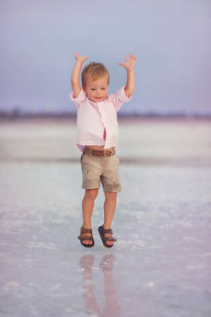 little cute boy in wet shorts jumping in the seaの写真素材