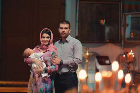 in the church baptized young family with a small child in her armsの写真素材
