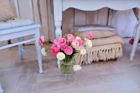 on the floor by the table a glass vase with a bouquet of pink ranunkulyusovの写真素材