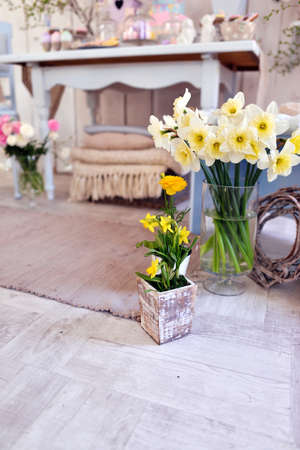 in the room on the floor is a vase with a bouquet of daffodilsの写真素材