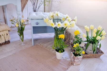 in the room on the floor is a vase with a bouquet of daffodilsの写真素材