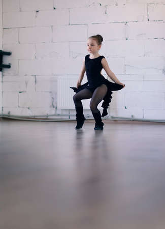 little ballerina in a black dress in pantyhose engaged in the hallの写真素材