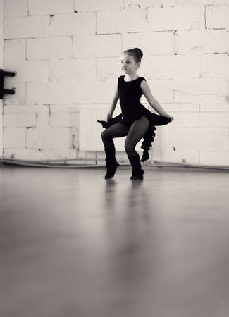 little ballerina in a black dress in pantyhose engaged in the hallの写真素材