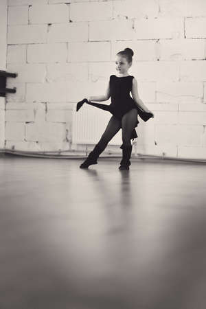 little ballerina in a black dress in pantyhose engaged in the hallの写真素材