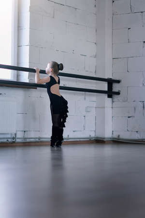 little ballerina in a black dress in pantyhose engaged in the hallの写真素材