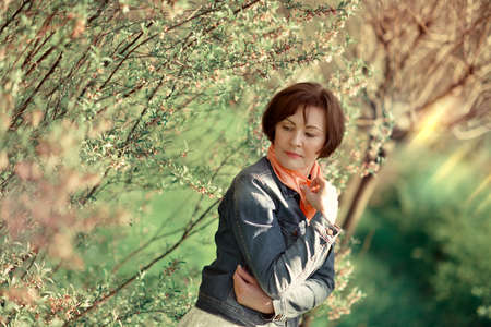 in the garden with flowering trees posing woman in a denim jacket