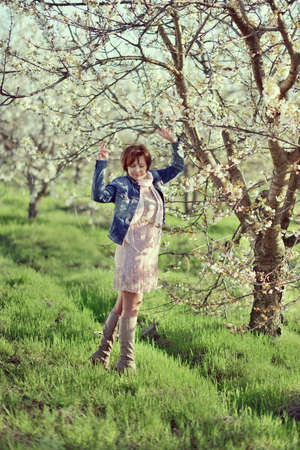 in the garden with flowering trees posing woman in a denim jacketの写真素材
