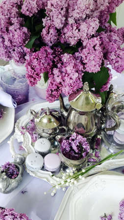 vase with a bouquet of lilacs on the table with silver tablewareの写真素材