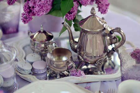 vase with a bouquet of lilacs on the table with silver tablewareの写真素材