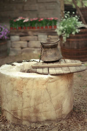 in the courtyard on the background of flowers and barrels round the well with a bucketの写真素材