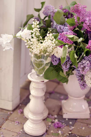on the floor are large white vases with bouquets of lilac and lily of the valleyの写真素材