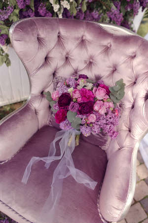 a silk purple chair lies a bouquet of lilacs and rosesの写真素材