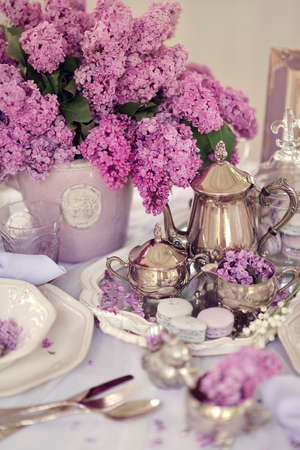 vase with a bouquet of lilacs on the table with silver tablewareの写真素材