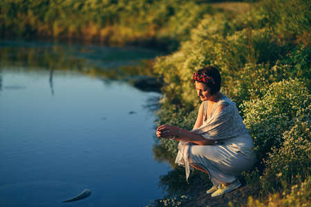 summer evening sitting by the river girl with a wreath daisiesの写真素材