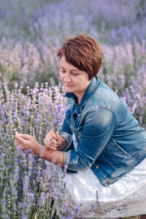 Portrait of beautiful romantic woman in fairy field of lavender with bouquetの写真素材
