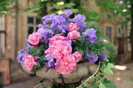 outside in the stone vase beautiful bouquet of pink peonies and blue irises