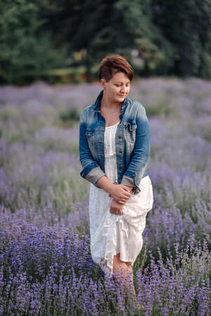 Portrait of beautiful romantic woman in fairy field of lavender with bouquetの写真素材