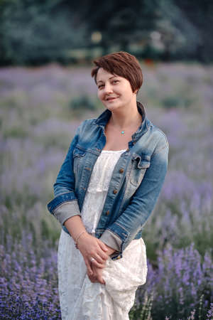 Portrait of beautiful romantic woman in fairy field of lavender with bouquetの写真素材