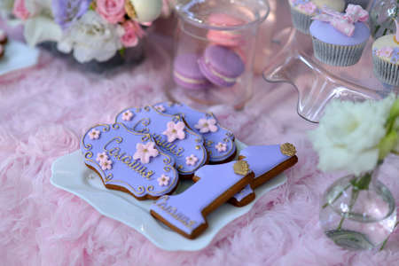 on the table with a pink tablecloth plate of biscuits covered with icing and flowersの写真素材