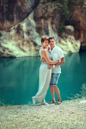 mountains in the background on the shore of the river are embracing man and womanの写真素材