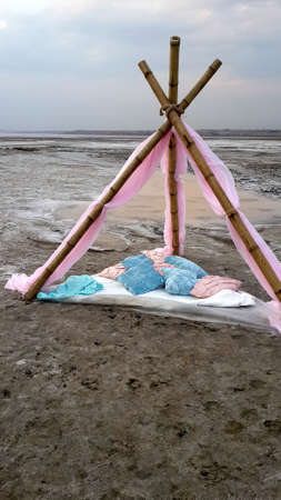 on the sand dunes is a canopy of bamboo and pink chiffon with pillowsの写真素材