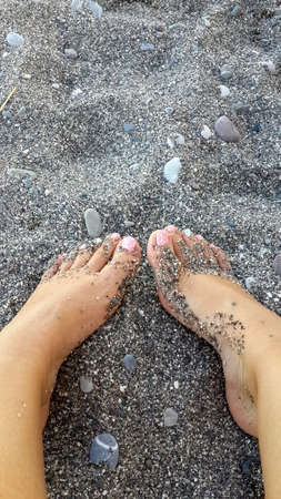 the sea on the pebbles with a beautiful female feet pedicure in the sandの写真素材