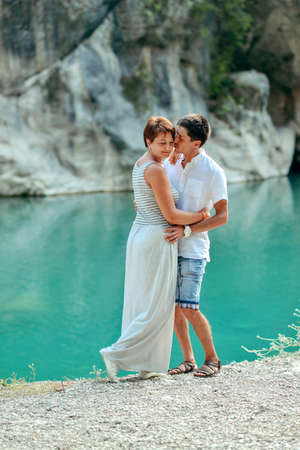 sunny summer day at the river on a background of azure rocks young beautiful coupleの写真素材
