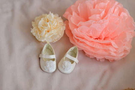 white baby shoes and large flowers made of paperの写真素材