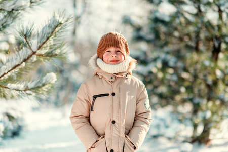 winter sunny day in the snowy forest walks boy in a cap with red cheeksの写真素材