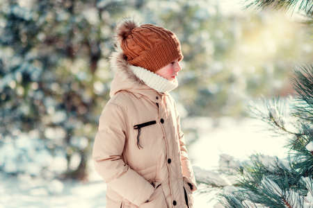 winter sunny day in the snowy forest walks boy in a cap with red cheeksの写真素材