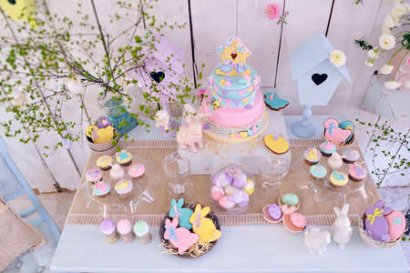 Easter decorations on the table, rabbits and cakes and colored eggs