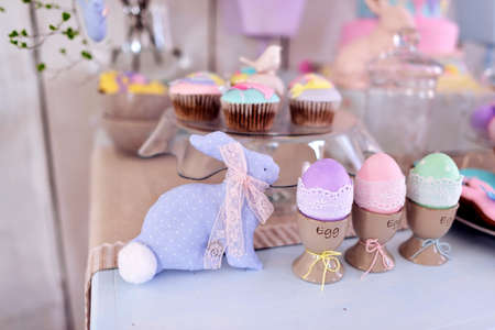 Easter decorations on the table, rabbits and cakes and colored eggs
