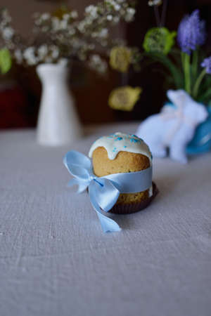 on the background of flowers and a rabbit Easter cake with blue ribbonの写真素材
