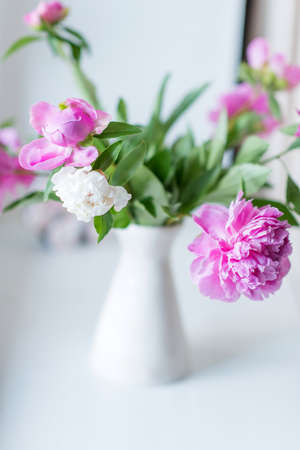 bouquet of white and pink peonies in white vase on the tableの写真素材