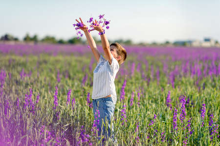 sunny day a little boy walks on the purple flowersの写真素材